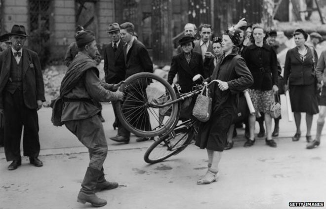 Советский солдат пытается взять женский велосипед в Берлине