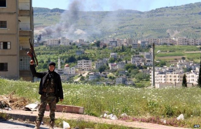 Сирийские повстанцы держат свою винтовку в воздухе возле Джиср аль-Шугур (25 апреля 2015 года)