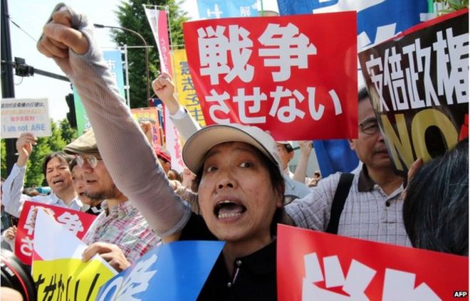 Активисты выкрикивают лозунги против японского премьер-министра Синдзо Абэ, когда около 500 протестующих собрались перед официальной резиденцией премьер-министра в Токио 14 мая 2015 года.
