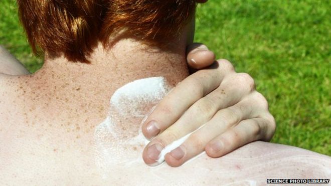 Человек, защищающий заднюю часть его шеи солнцезащитным кремом