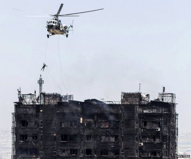 Спасатель спускается с вертолета над крышей сгоревшего многоэтажного жилого дома в Баку, Азербайджан, 19 мая 2015 года