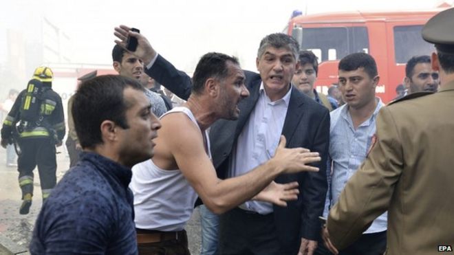 Разъяренные азербайджанцы спорят с пожарными и полицией на месте горящего 16-этажного жилого дома в Баку, Азербайджан 19 мая 2015 года