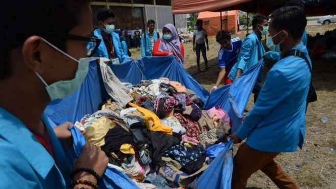 На этой фотографии, сделанной 17 мая 2015 года, индонезийские добровольцы несут пожертвованную одежду для спасенных мигрантов на складе, преобразованном в кварталы в рыбацком порту Лангса в провинции Ачех.