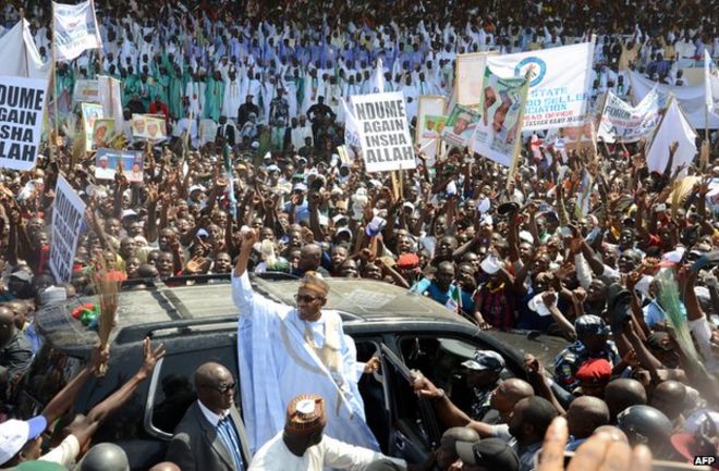 Мохаммаду Бухари (С) поднимает руку во время предвыборного митинга партии в Майдугури 16 февраля 2015 года.