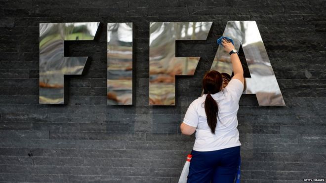 Женщина вытирает логотип ФИФА