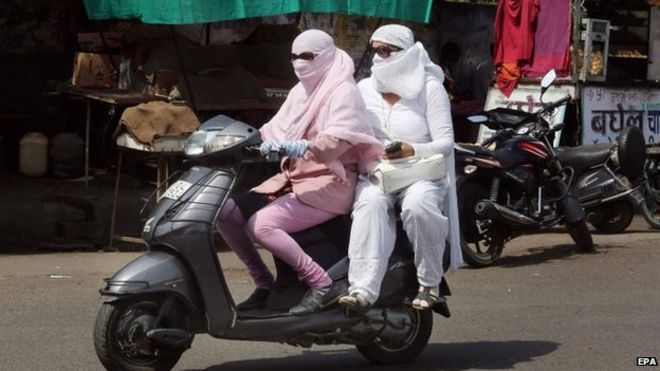 Индийские мотоциклисты прикрыты, чтобы защитить себя от палящей жары в Бхопале, Индия, 28 мая 2015 года.