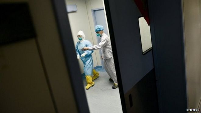 Медицинский персонал проходит мимо двери отделения интенсивной терапии в больнице, где 1 июня 2015 года в Хуэйчжоу, провинция Гуандун, Китай, находится на карантине и проходит лечение пациент MERS из Южной Кореи.