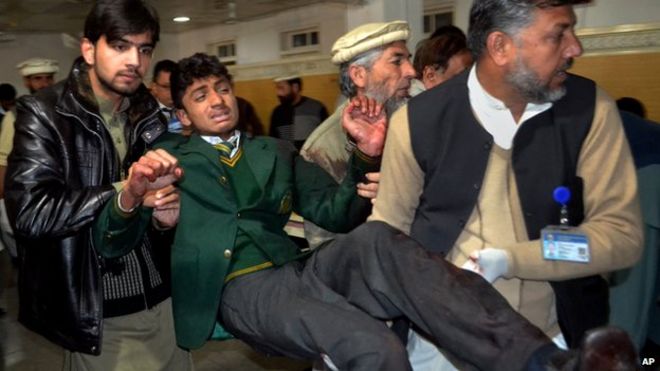 Пакистанские добровольцы несут студента, пострадавшего в перестрелке в школе, подвергшейся нападению боевиков талибов