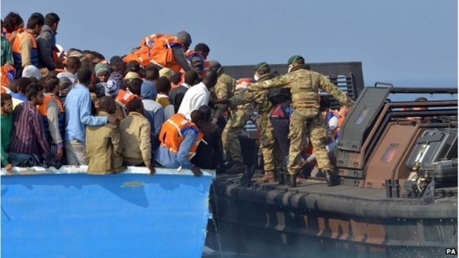Королевские морские пехотинцы из HMS Bulwark помогают спасать мигрантов, застрявших на лодке в тридцати милях от ливийского побережья.