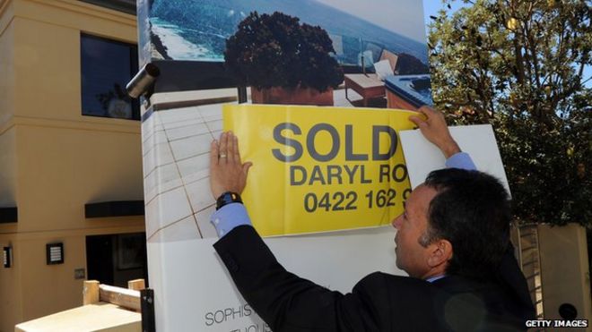 Агентство недвижимости размещает проданную наклейку над вывеской в ??собственности Сиднея
