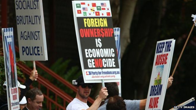 Протестующий против китайских иностранных инвестиций держит плакат возле консульства Китая в Сиднее