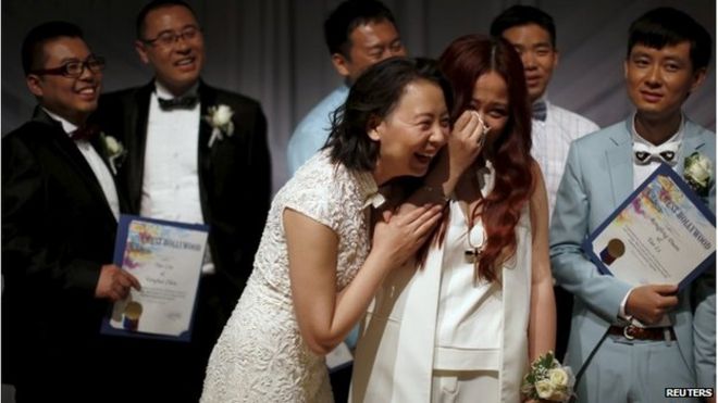 Сю На (в центре L) обнимает свою новую жену Сюэ Мэнъяо (в центре R) после их свадьбы в Западном Голливуде (9 июня 2015 г.)