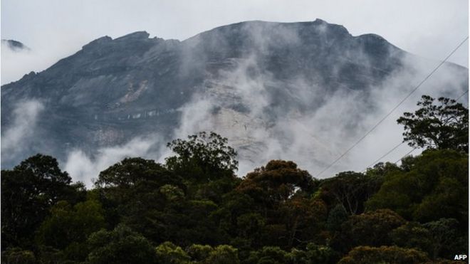 Малайзийская гора Кинабалу видна среди туманов на контрольно-пропускном пункте у ворот Тимпохона на следующий день после землетрясения в Кундасанге, городе в районе Ранау 6 июня 2015 года