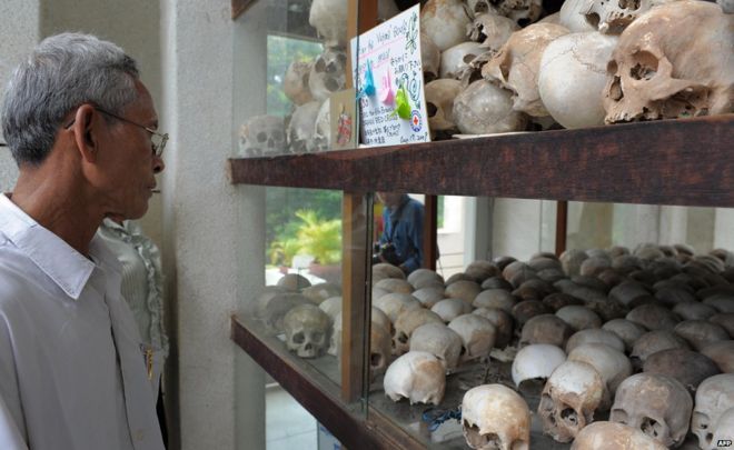 Посетитель смотрит на черепа на Туол Сленг