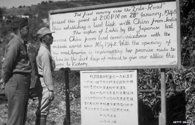 Американец и китайский солдат читают табличку с описанием первого конвоя через Ледо-Бирма-роуд, связывающего Китай с Индией.