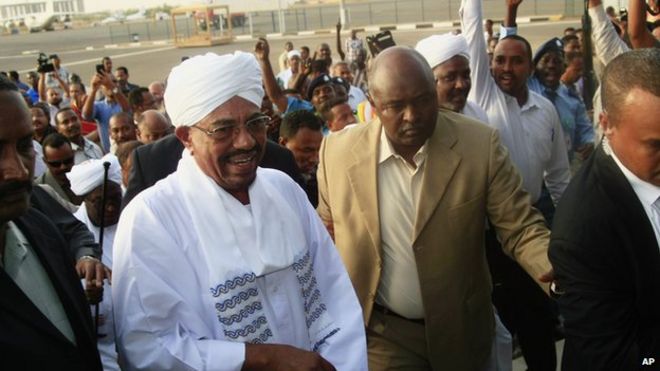 Сотни сторонников приветствуют президента Судана Омара аль-Башира (в центре слева) по прибытии из Южной Африки, когда он идет сквозь толпу в аэропорту Хартума