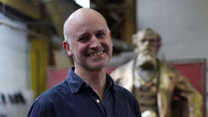 Martin Jennings, a bald man wearing a blue shirt and grinning.