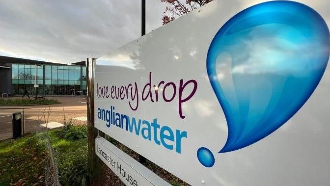 A sign outside a glass building that reads "Love every drop, anglian water" beside an image of a drop of water. 