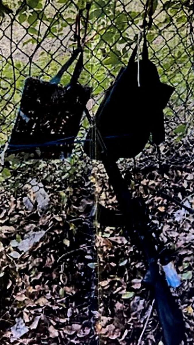 Bags hang from a fence over a rifle propped against it, in an image provided by Palm Beach County Sheriff's Office