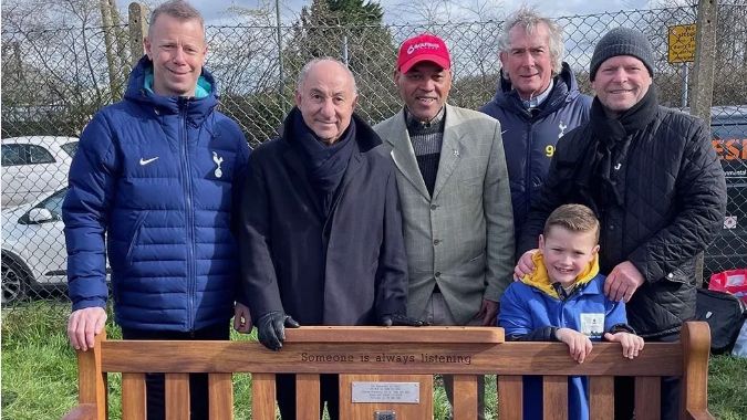 A group, including Micky Hazard, Ossie Ardiles and Bryan Hughes, stand behind a memory bench