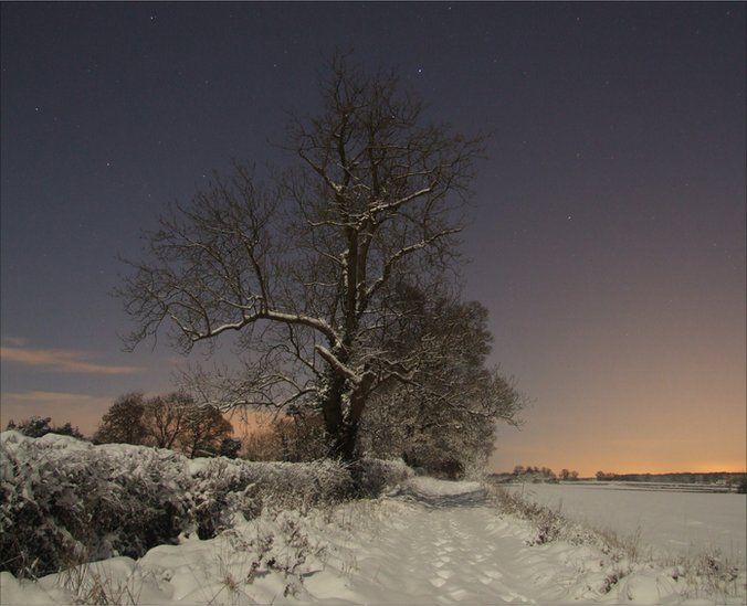 A full moon on a clear night illuminates the heavy snowfall in Oxfordshire, UK