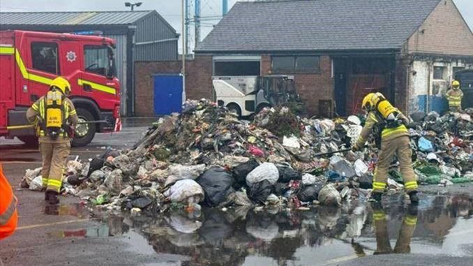 Firefighters monitoring a pile of waste at the depot