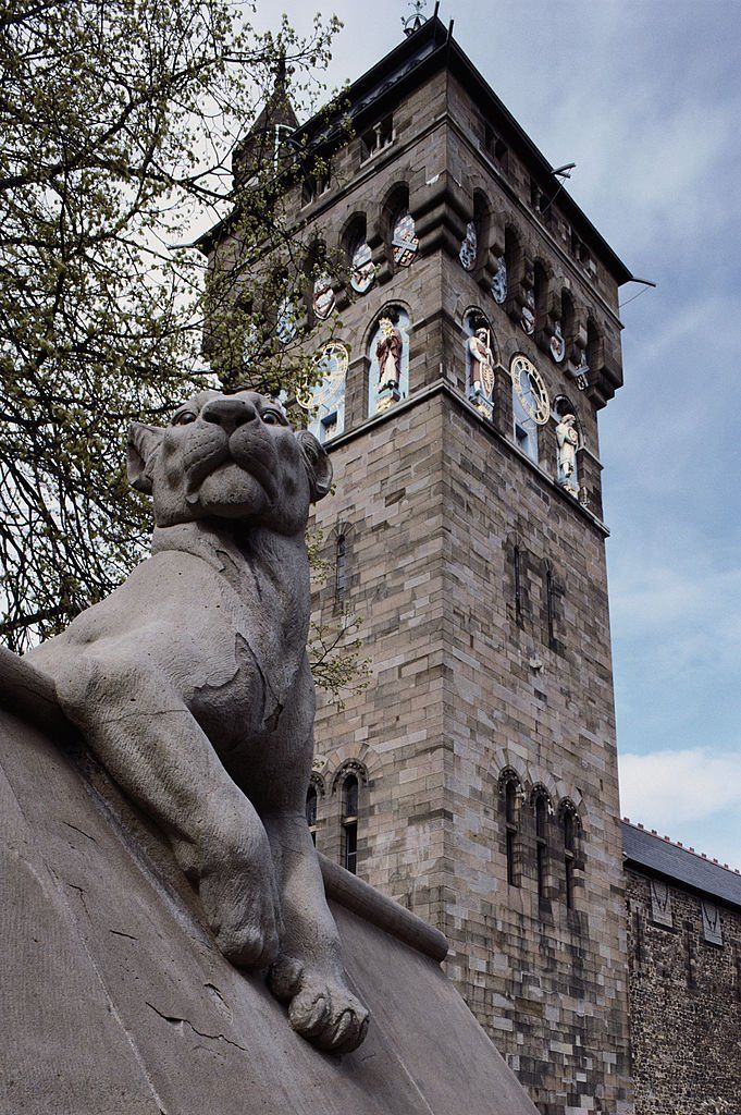 A view of the castle clock tower and one of the 15 animals incorporated into the wall along Castle street, Cardiff, Wales