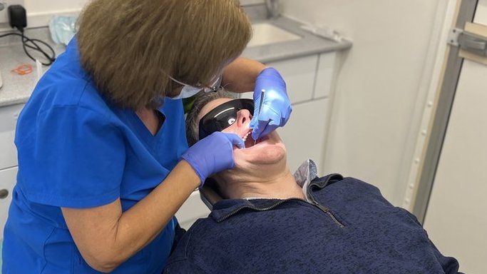 Dentist treats patient on mobile dental unit