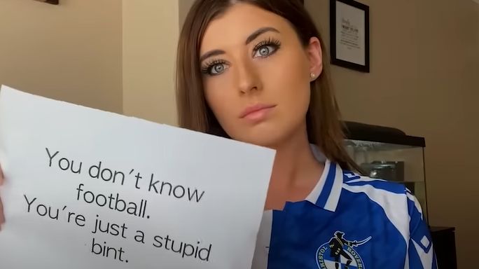 Woman with poster saying 'you don't know football. You're just a stupid bint'