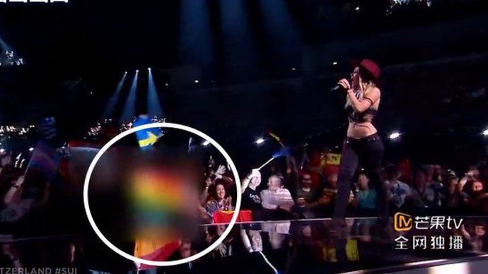 Screenshot of Switzerland's Eurovision performance with a rainbow flag in the audience blurred out and circled