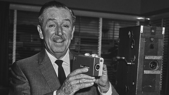 Walt Disney holds a camera 
