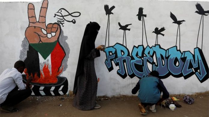 Demonstrators in Khartoum paint a mural reading "Freedom", 14 April 2019