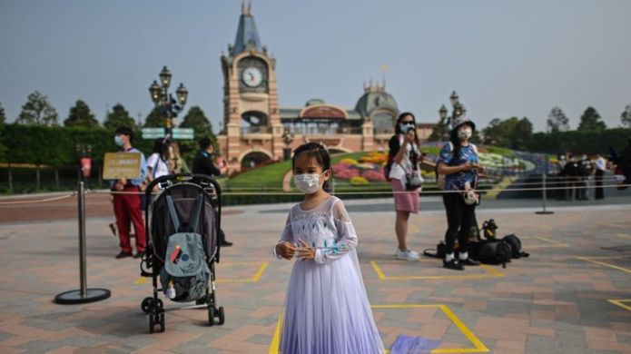 A girl wearing a face mask waits to enter the Disneyland amusement park in Shanghai on May 11, 2020