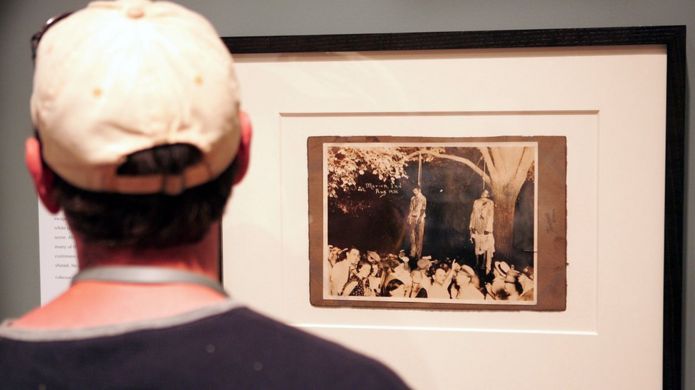 A man watches an exhibition of photographs of lynchings in the United States.
