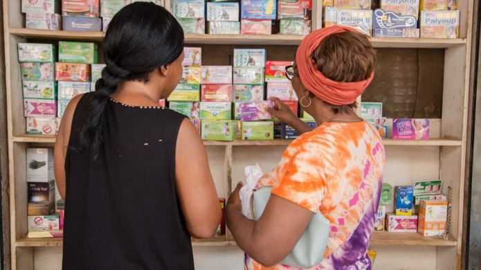 Dos mujeres miran un estante con productos de medicina tradicional.