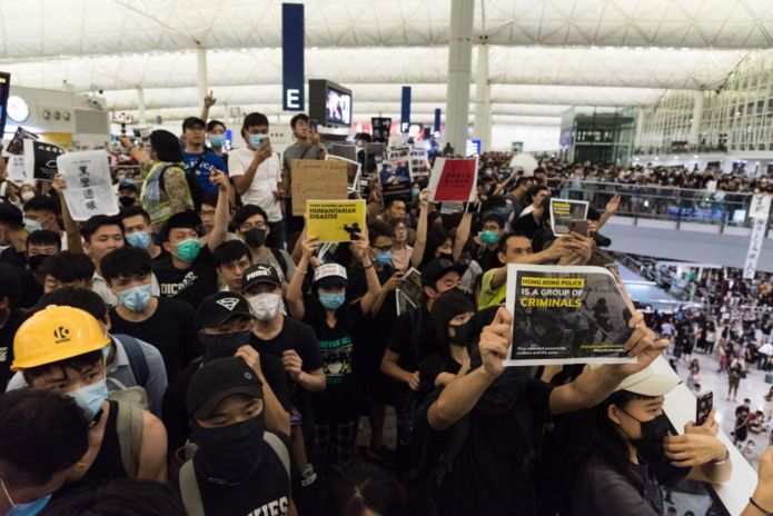 Người biểu tình giơ cao biểu ngữ chống chính phủ tại sân bay quốc tế Hồng Kông trong ngày thứ 5 liên tiếp cho đến tận chiều tối