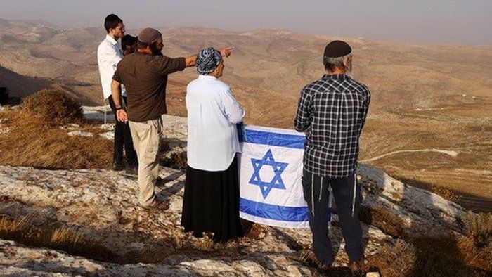 Jewish people with an Israeli flag on a hilltop in the West Bank (06/11/22)