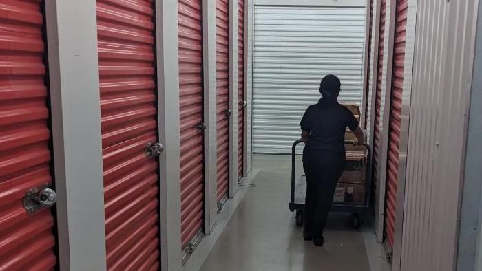 A lady pushes a trolley down the aisle of a self-storage facility