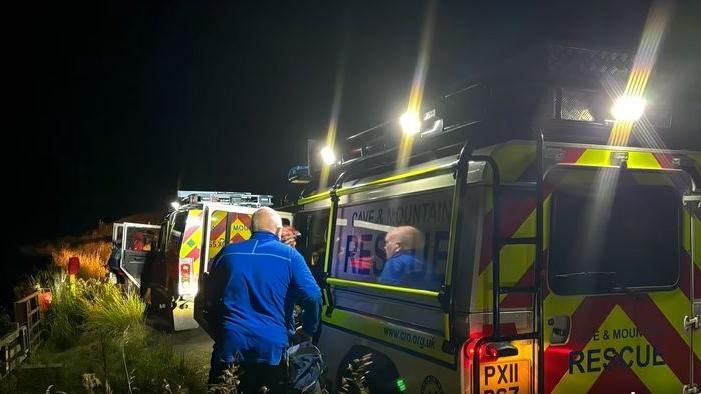 Emergency vehicles and cave rescue volunteers on Whernside at night