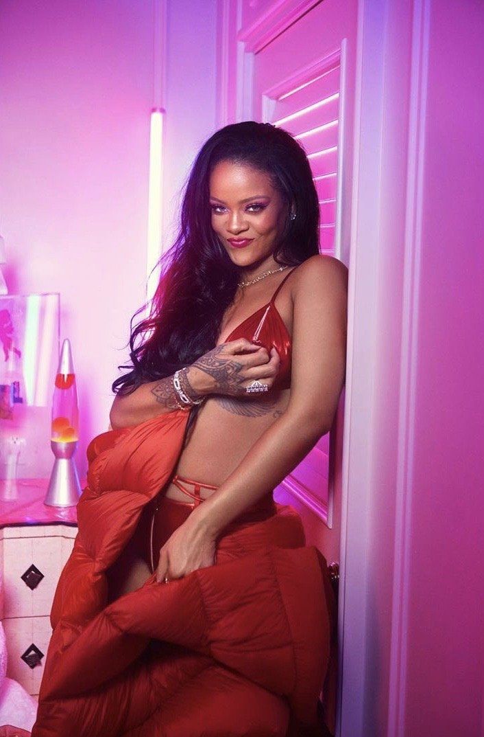 Rihanna smiles in her latest collection for Savage X Fenty in red satin bra set and a red long puffer jacket