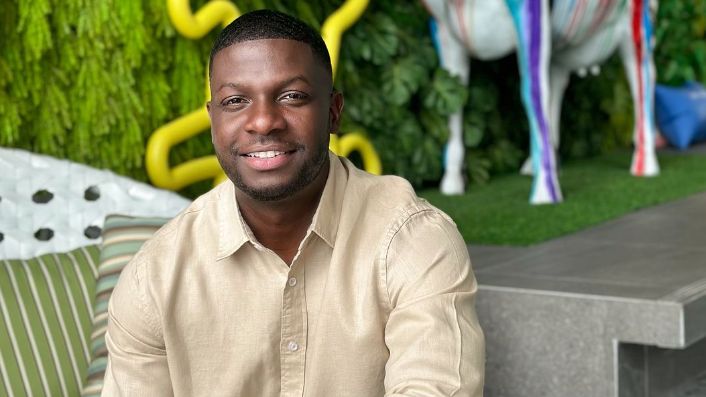 Damion Bailey in beige shirt sitting in a garden