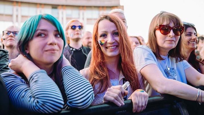 Three female Placebo fans smile at the camera from the front row at Bristol Sounds 2024