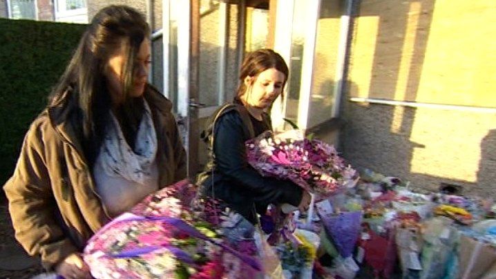 People leaving flowers outside the house the victims died