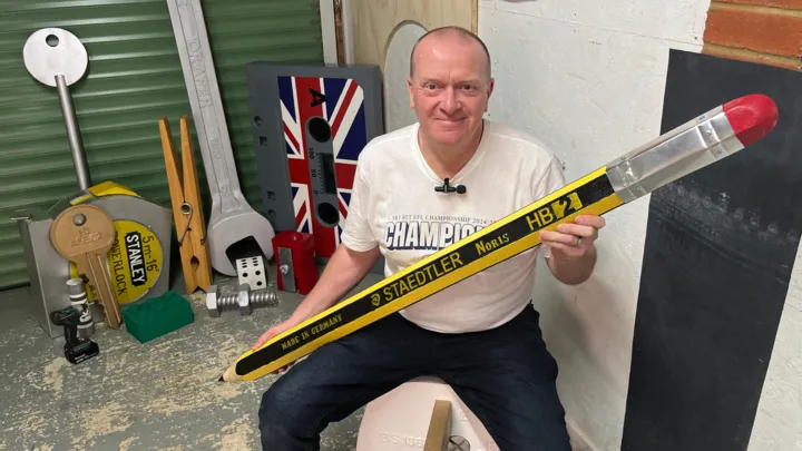 Steve Wainwright beside his giant pencil in his garden workshop