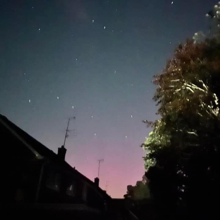 Pink and purple sky fading to black, with white stars. In the foreground are silhouettes of buildings