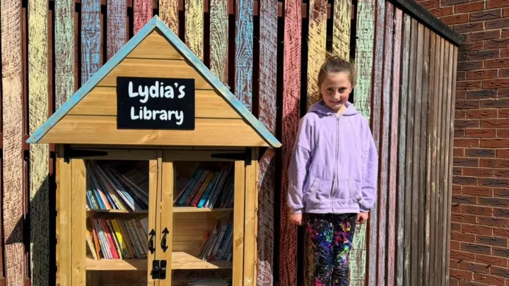 Lydia Lawless standing beside her handmade mini library