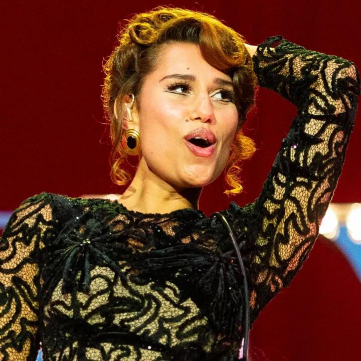 Getty Images Raye smiles as she performs on stage in a black ballgown