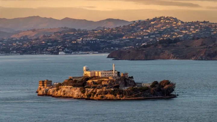 A distant view of Alcatraz Island with the Golden Gate Bridge visible in the background