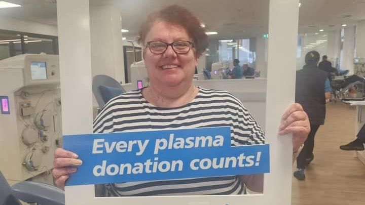 A woman holding a plasma donation selfie aid