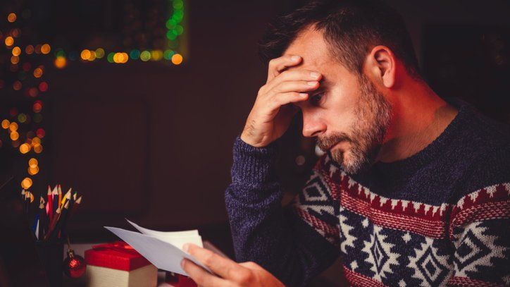 stressed man looking at a letter at Christmas